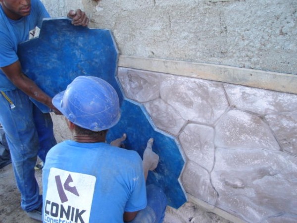 Operários trabalhando da desforma de concreto estampado para paredes