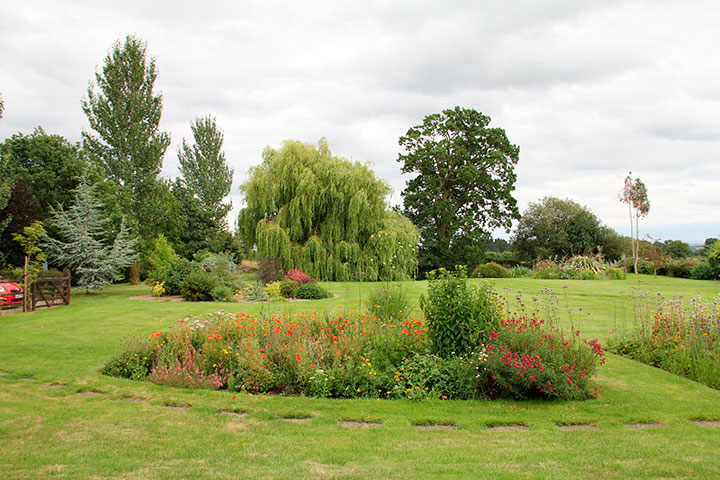 Jardim de residência inglesa em que os canteiros e arvoredos são plantados de forma que pareçam o mais natural possível.