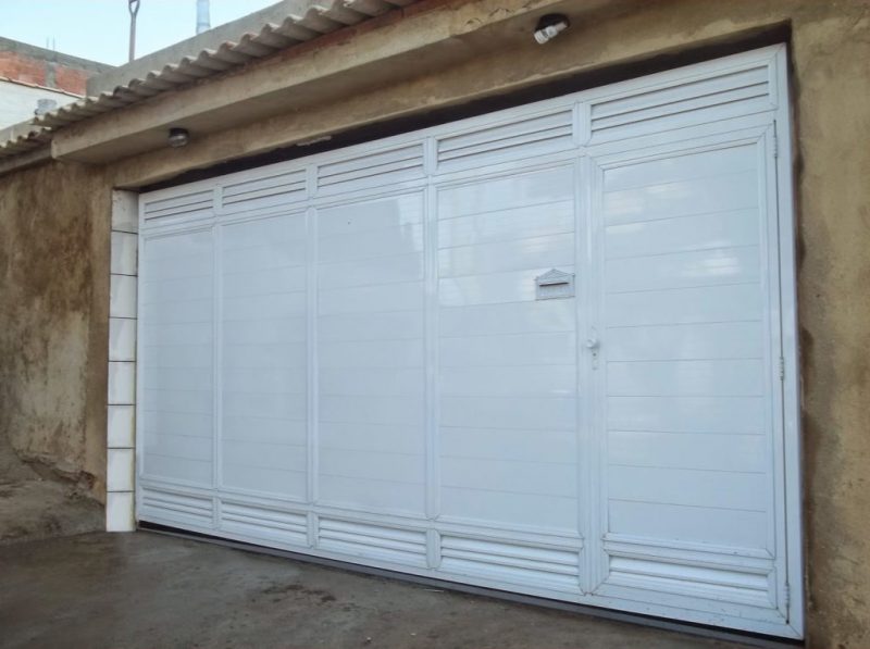 Portão de chapas brancas, fazendo o fechamento de garagem, feito inteiramente de perfis e chapas de alumínio